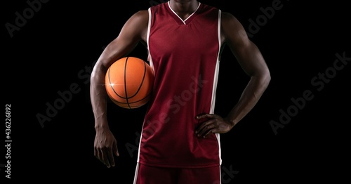 Composition of midsection of male basketball player with ball and copy space on black background © vectorfusionart