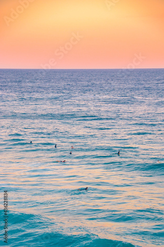 Fototapeta Naklejka Na Ścianę i Meble -  Surfers in the water at sunset waiting for a wave