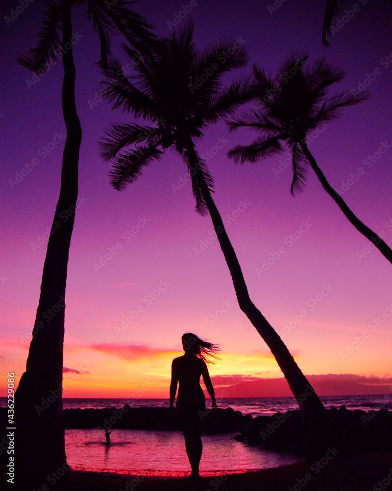 Fototapeta premium Woman walking towards the purple and pink sunset