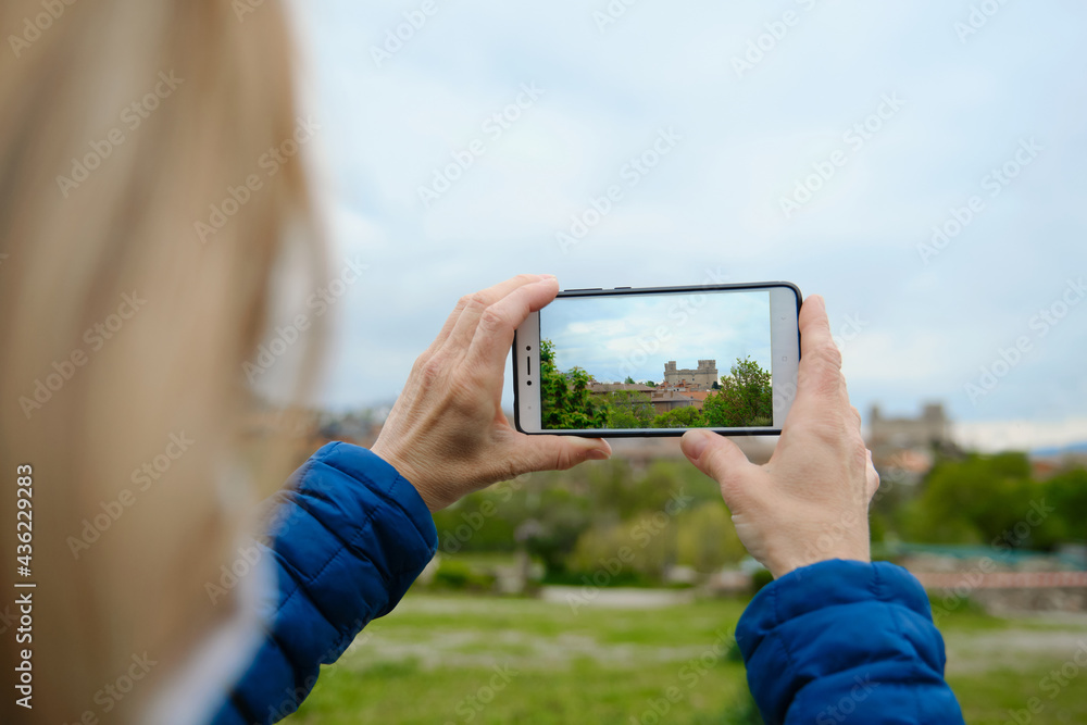 Unrecognizable woman taking a picture with her mobile phone of the castle of Manzanares El Real
