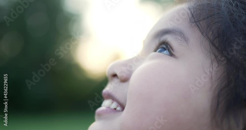 Happy asian kid girl looking up at sky in nature