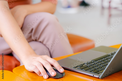 Casual woman  freelance working on laptop computer and clicking wireless digital mouse.