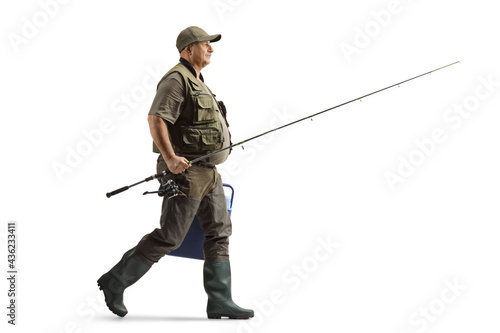 Fotografie, Obraz Full length profile shot of a mature fisherman in a uniform walking with a fishi