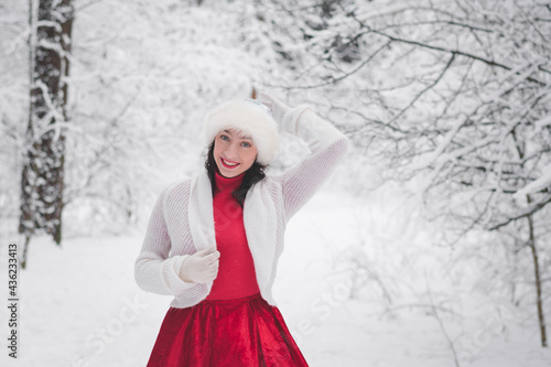 Beautiful girl in winter snowy forest in christmas clothes