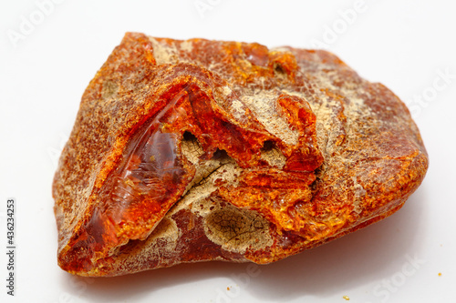 A beautiful transparent piece of natural amber on a white background. Sun stone. Red-yellow background. Fossilized ancient resin. Copal. Semi-precious mineral for jewelry. Amber texture 