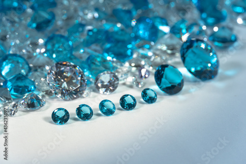 A group of aquamarine blue diamonds arranged in the middle of white diamonds on a white background.. © Narong Niemhom