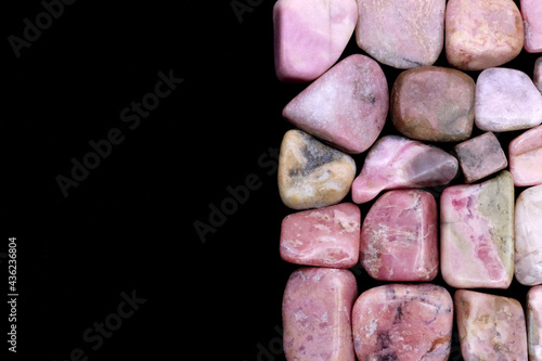 Rhodochrosite heap jewel stones texture on half black background. Place for text. photo