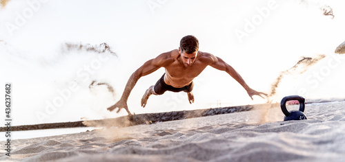 Fitness handsome man exercising on the beach during sunset, outdoor. Personal trainer working out. photo