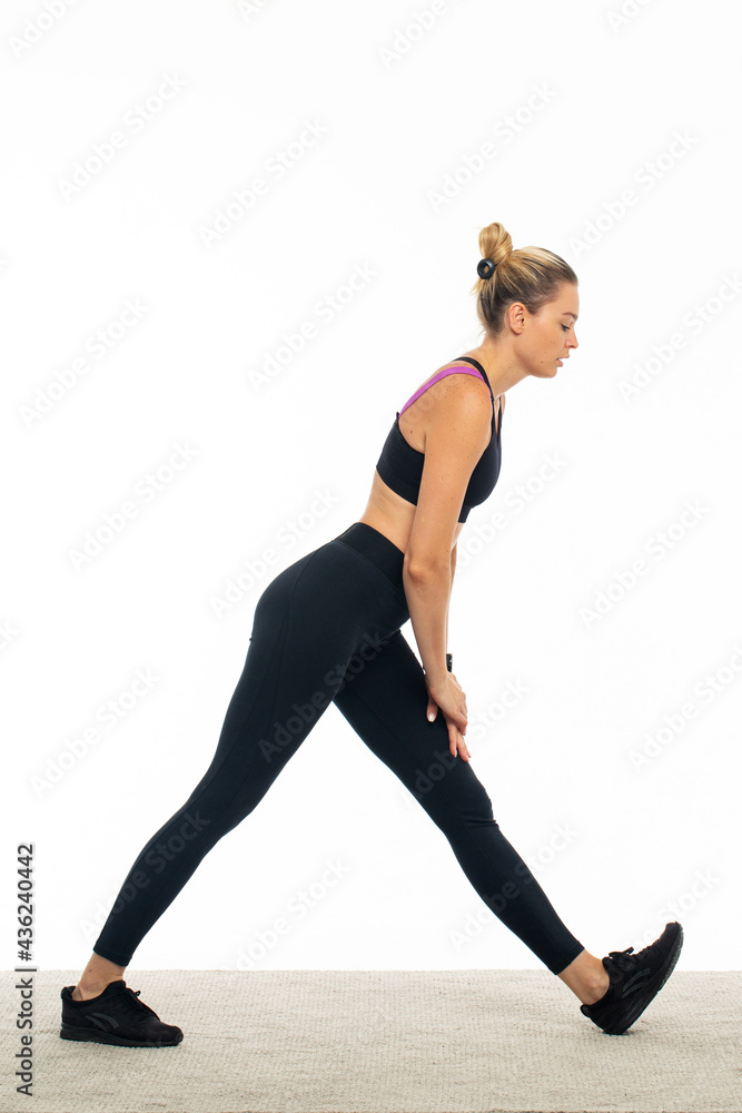 Fototapeta premium Young sportswoman stretching in studio