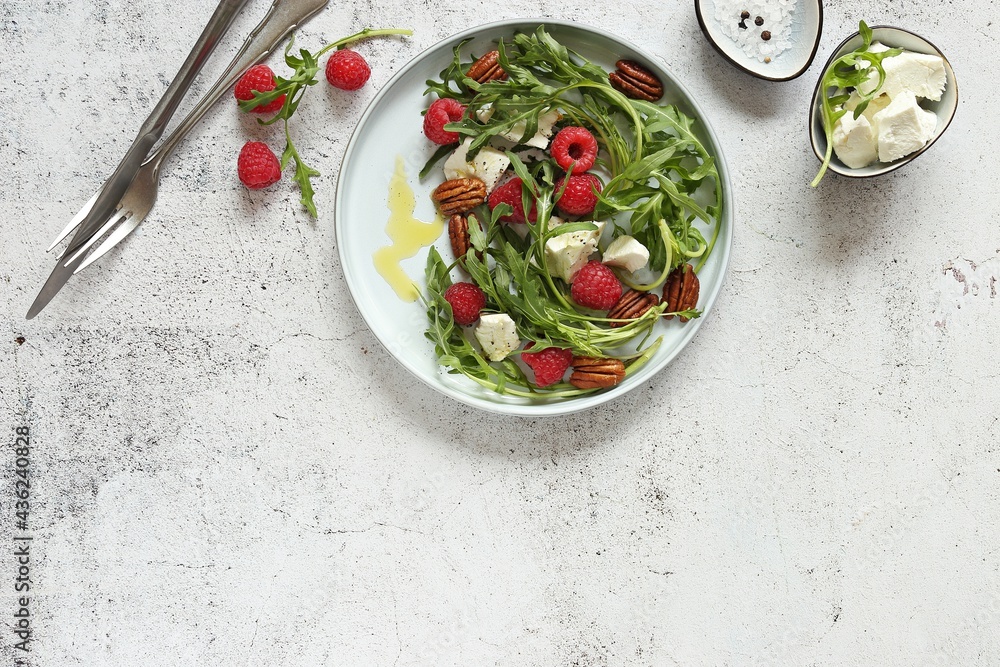 Arugula salad with raspberry, goat cheese and caramelized pecans . Flat layot_ copy space Arugula salad with raspberry, goat cheese and caramelized pecans . Flat layot_ copy space