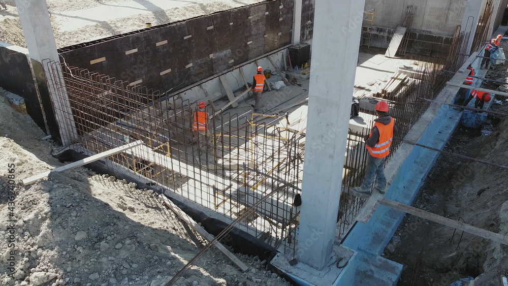 Large construction site of residential building with workers. Modern monolithic construction. Many different workers on the construction site. Construction of reinforced concrete structures