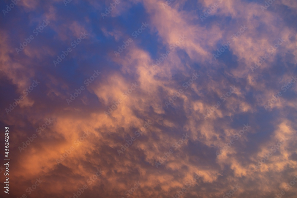 Sunbeams through colorful clouds on blue sky background.