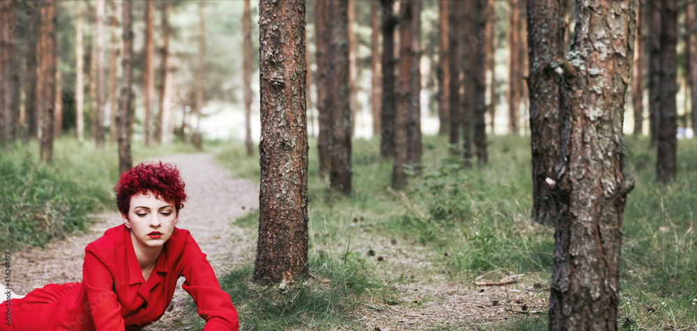 Young woman in red dress posing in pine forest Young woman in red dress posing in pine forest