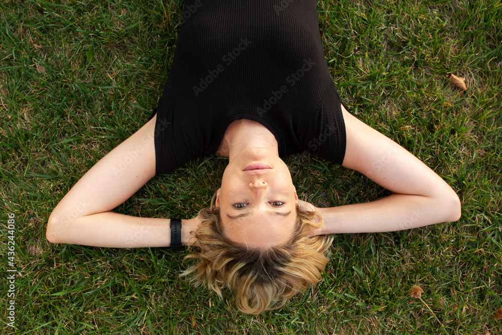 Young blonde woman lying on green grass Young blonde woman lying on green grass