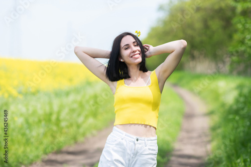 Portrait of a young beautiful girl in front of a yellow rapeseed field