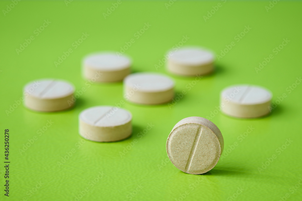 Medical pill closeup on green background. Medical drugs pills. Healthcare, pharmaceuticals and chemistry concept, shallow depth of sharpness Medical pill closeup on green background. Medical drugs pills. Healthcare, pharmaceuticals and chemistry concept, shallow depth of sharpness