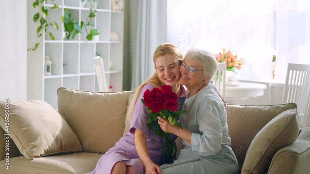 Young girl gives flowers to aged lady with joyful smile at birthday Young girl gives flowers to aged lady with joyful smile at birthday