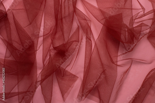 Texture of wrinkled, crumpled red tulle fabric on a pink background close-up. background for your mockup