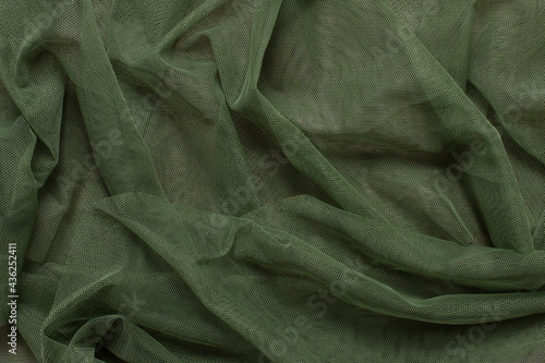 Texture of wrinkled, crumpled green tulle mesh fabric on a pink background close-up. background for your mockup