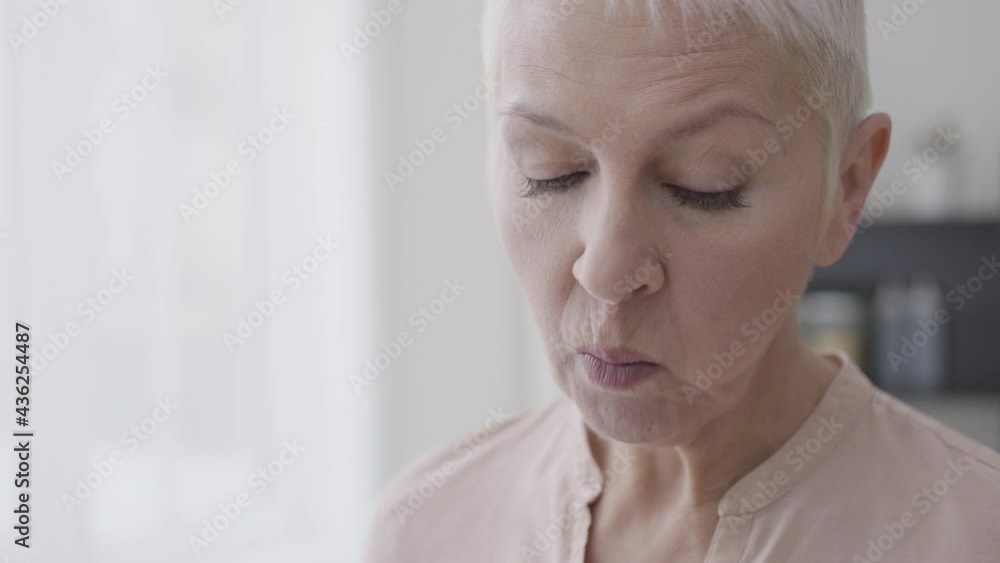 Middle-aged woman eating nuts and smiling, enjoying healthy snack, dieting Middle-aged woman eating nuts and smiling, enjoying healthy snack, dieting