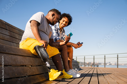 Print op canvas disabled black man showing mobile screen to friend.