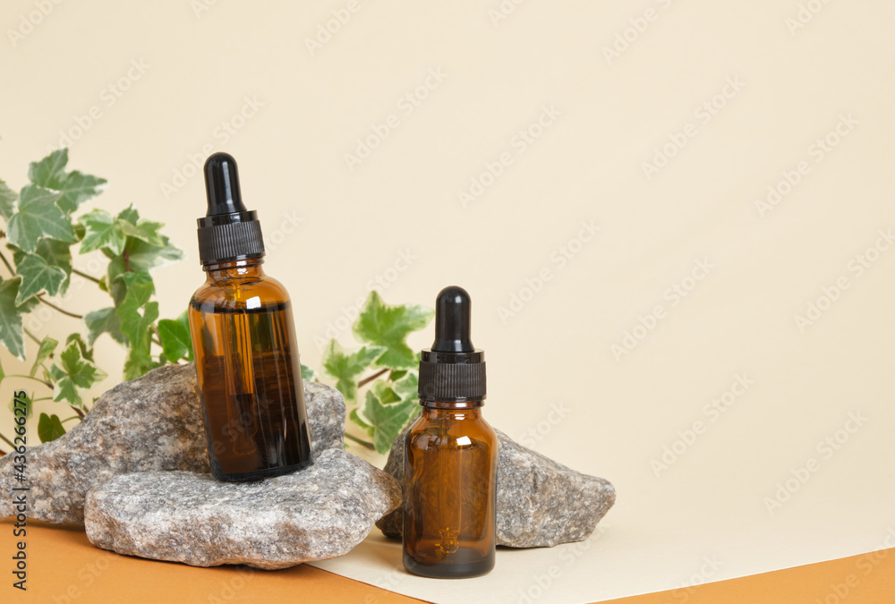 brown bottles for cosmetics with a pipette on a beige background, stones and a plant on the background, zero waste lifestyle