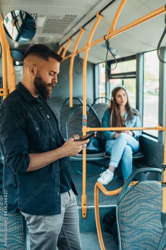 Young handsome man riding a bus while using a smartphone