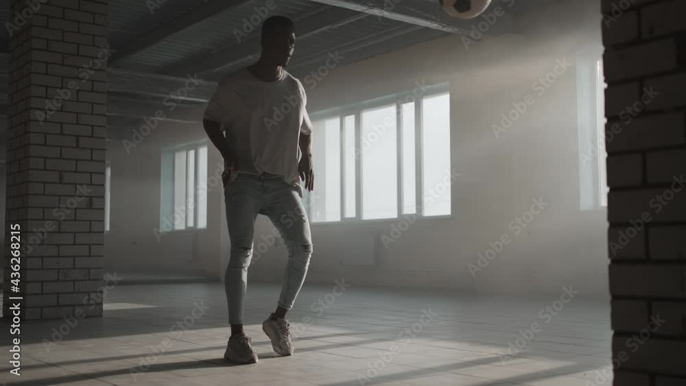 African-American guy trains in freestyle football and his skill for a professional game in an underground parking lot in the dark African-American guy trains in freestyle football and his skill for a professional game in an underground parking lot in the dark