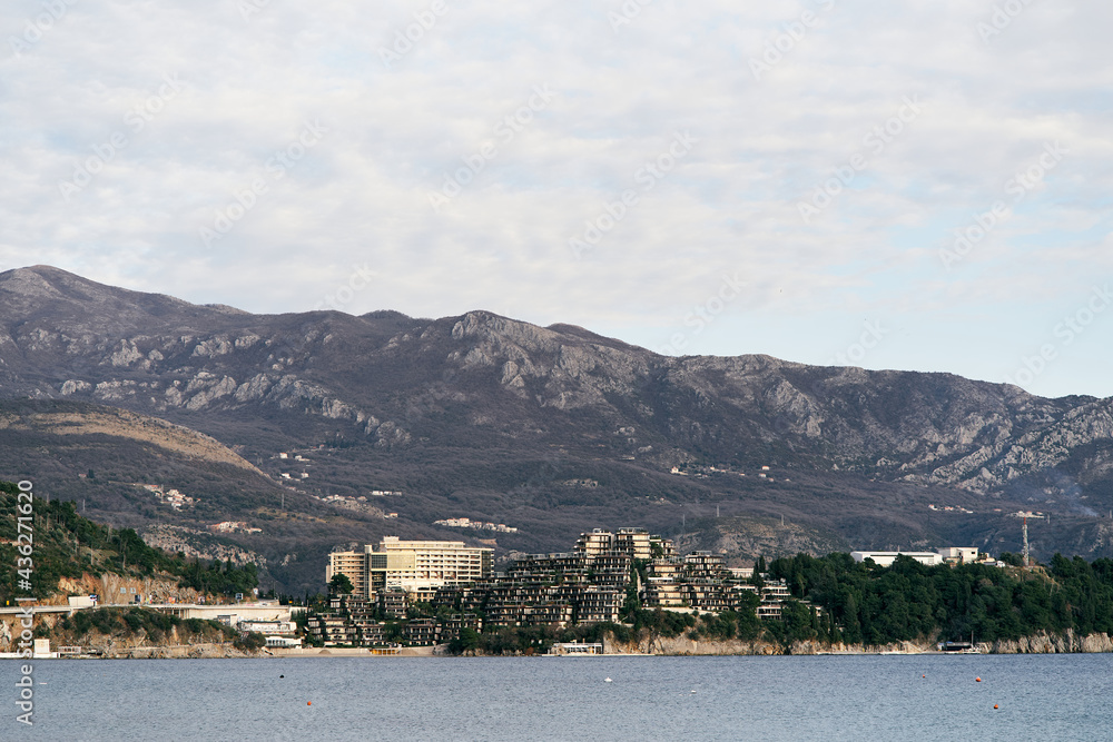 View from the sea to the coast with houses and green trees around against the backdrop of mountains