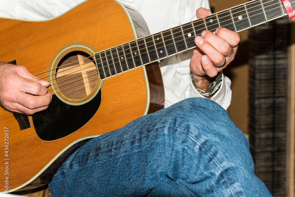 Fototapeta premium Detail of a man's hands playing an acoustic steal string guitar.