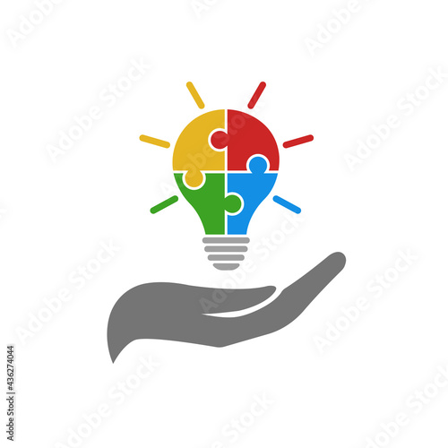 Light bulb vector icon from colorful jigsaw puzzle pieces on the hand. Four puzzle pieces connected to each other. Vector illustration isolated on white	