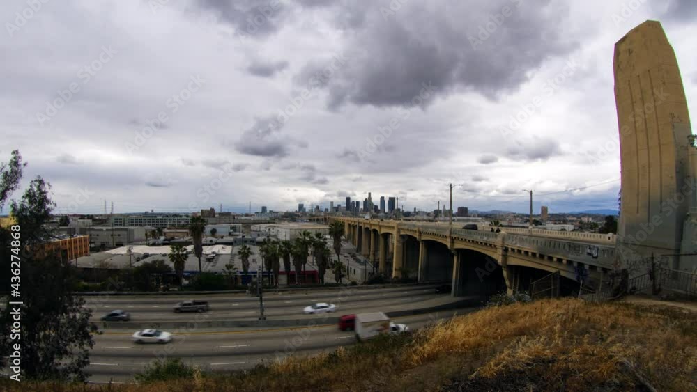 Lockdown Time Lapse Shot Of Vehicles Moving On Road Against Cloudy Sky, Tall Buildings In City - Los Angeles, California Lockdown Time Lapse Shot Of Vehicles Moving On Road Against Cloudy Sky, Tall Buildings In City - Los Angeles, California