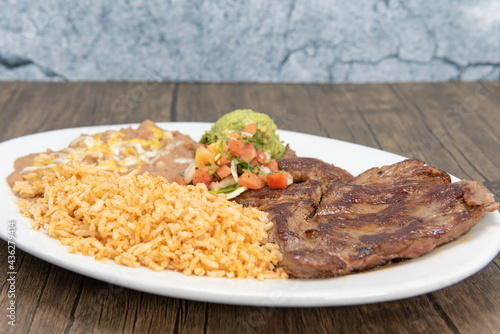 Принти на полотні Carne Asada steak cooked to perfection and served with rice and beans on a plate