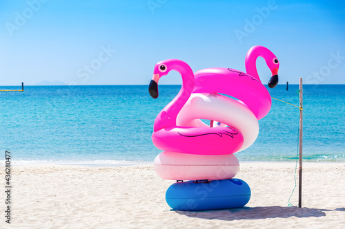 Fantasy Swim Ring and inflatable flamingo balloon on the sandy beach with blue sky and sea