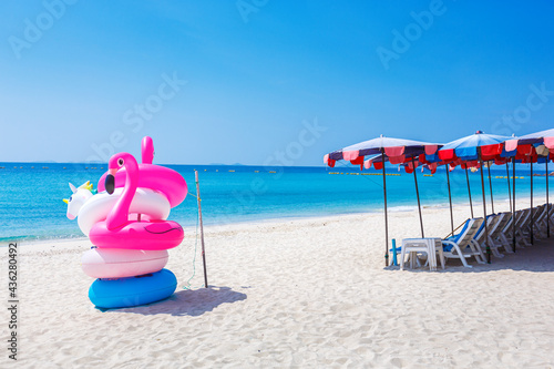 Fantasy Swim Ring and inflatable flamingo balloon on the sandy beach with blue sky and sea