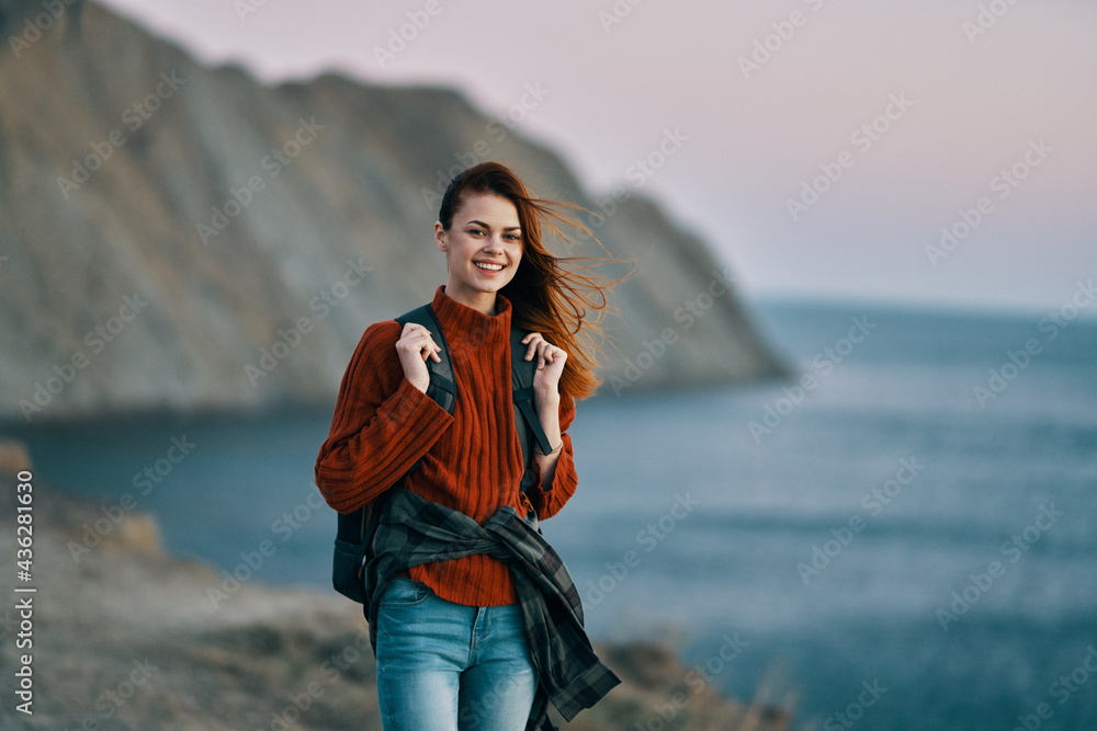 traveler with a backpack in the mountains in nature near the sea