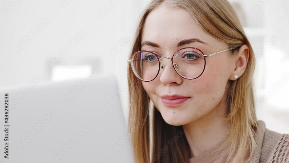 Portrait female face caucasian millennial young girl blonde student woman freelancer wears glasses looking at laptop screen working study remotely at computer using service application website online Portrait female face caucasian millennial young girl blonde student woman freelancer wears glasses looking at laptop screen working study remotely at computer using service application website online