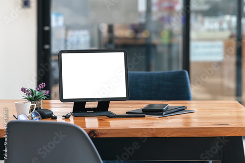 Mockup blank screen tablet with stand holder and gadget on wooden table in co-workspace. © NAMPIX