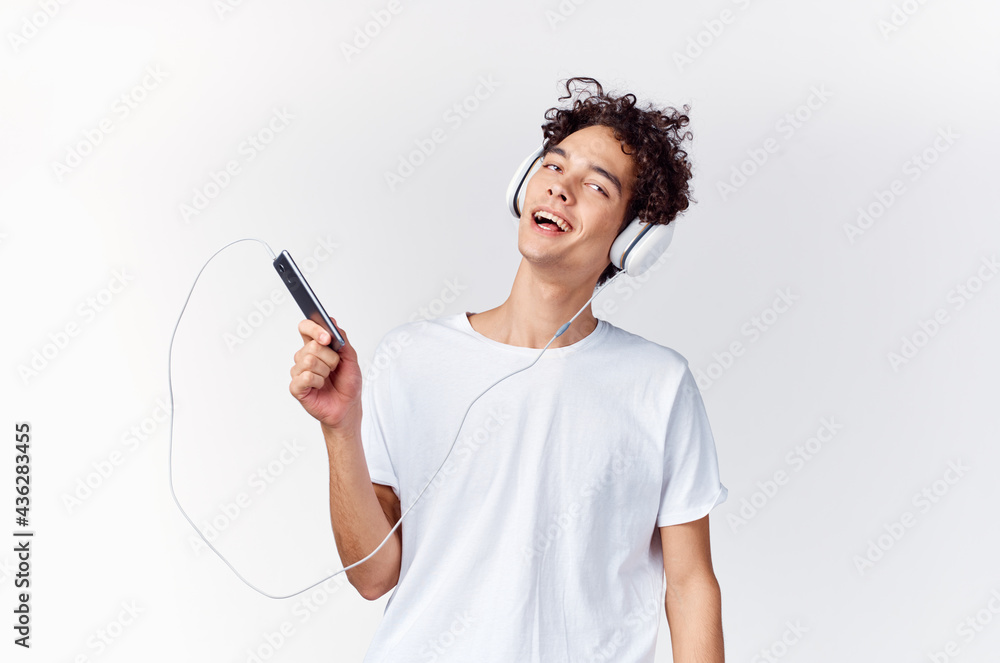 curly-haired guy in headphones with a phone in his hands music technology curly-haired guy in headphones with a phone in his hands music technology