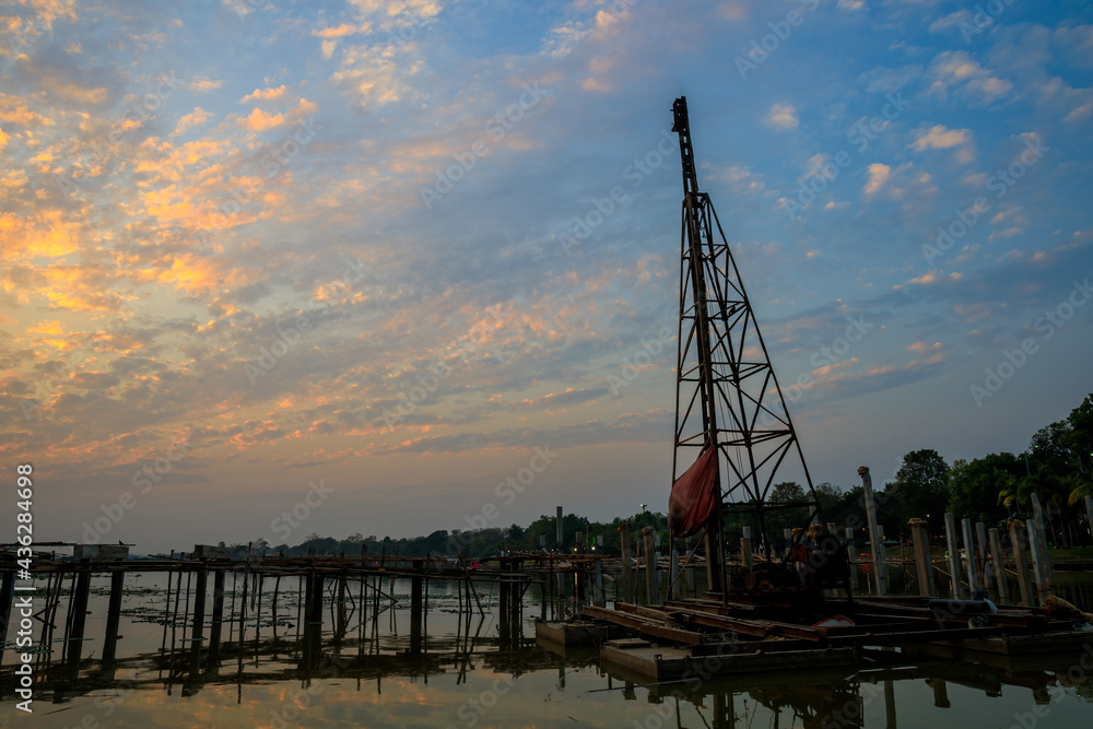 Stake crane at under construction site on the water lake at sunset or evening time with clouds scape. Stake crane at under construction site on the water lake at sunset or evening time with clouds scape.