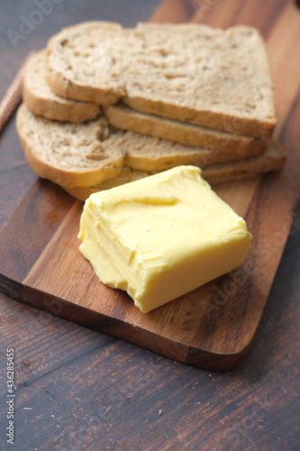 slice of butter and whole meal bread on chopping board 