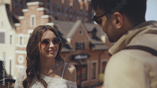 happy woman in sunglasses looking at blurred man. © LIGHTFIELD STUDIOS