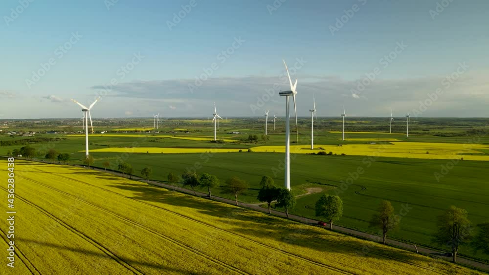 Aerial view of wind turbine farm in Puck Poland. Rapeseed blooming. Windmills and yellow fields from above. Drone flying around Agricultural fields on a summer day. Renewable Energy. Aerial view of wind turbine farm in Puck Poland. Rapeseed blooming. Windmills and yellow fields from above. Drone flying around Agricultural fields on a summer day. Renewable Energy.