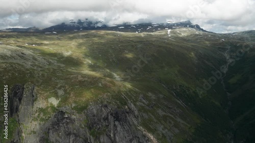 Aerial view of the vast Aurlandsfjellet mountain range. Green grass and moss cover hills and mountains. The thick blanket of white clouds moves over the plateau casting shadows. photo