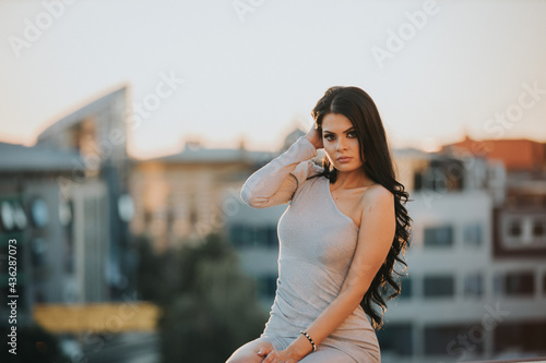 Brunette female model posing in an elegant dress with one sleeve photo