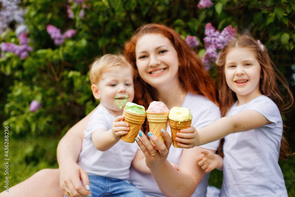 Selective focus. A happy family holds an open-air ice cream in front of them in a spring park against the background of blooming lilacs. Selective focus. A happy family holds an open-air ice cream in front of them in a spring park against the background of blooming lilacs.