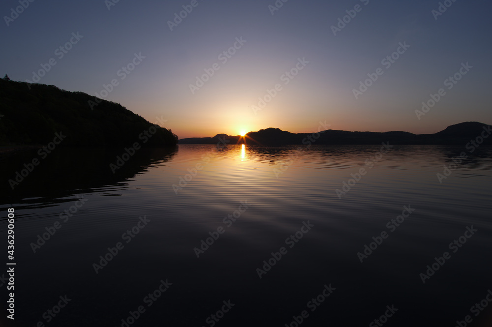暗闇から朝日の昇る夜明けの湖。