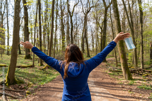 femme de dos se baladant en forêt au printemps libérée de son masque contre le covid 19