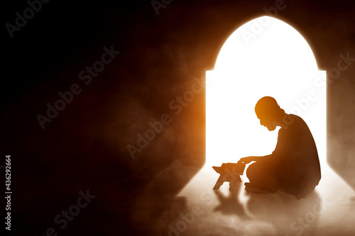 Silhouette of muslim man reading koran