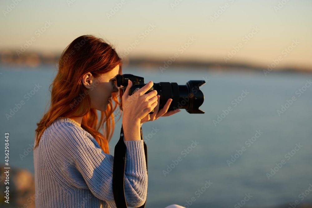 woman with professional camera at sunset by the sea